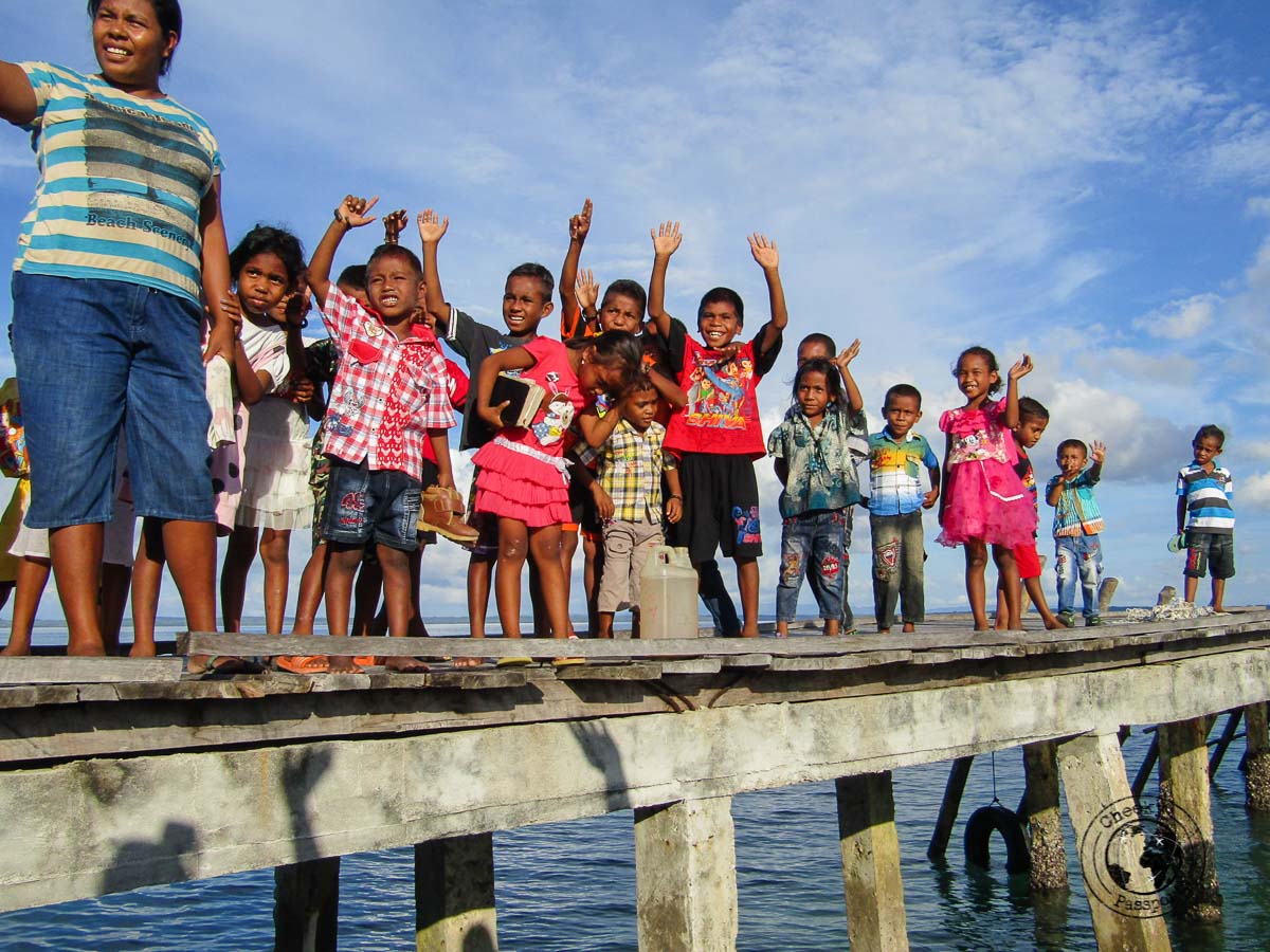Children waving farewell at a boatload of tourists at Bair island, in the Kei islands